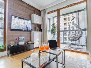A modern living room with a glass coffee table, a laptop, and two glasses of orange juice. - Warsaw Flat With Quiet Loggia (Warsaw)