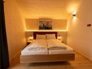 Ein Schlafzimmer mit einem Bett, Holzwänden, einem Gemälde und zwei Nachttischlampen.