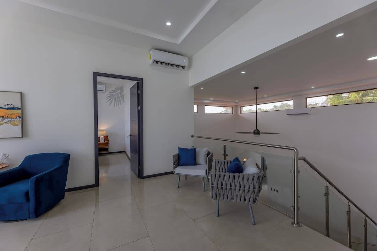 A modern hotel lobby with a reception desk, seating area, and a staircase.