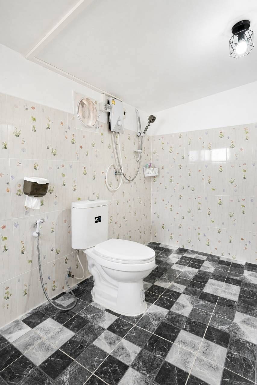Uma casa de banho com sanita, chuveiro e secador de mãos.