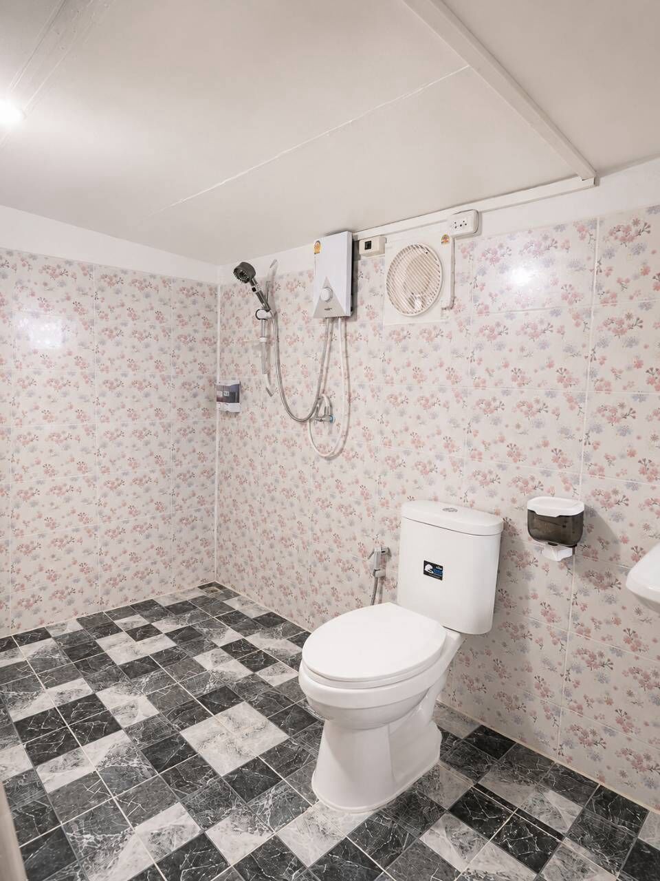 A bathroom with a toilet, a shower, and a hand dryer.