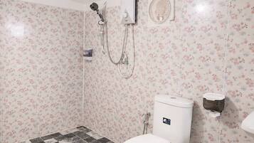 A bathroom with a toilet, a shower, and a hand dryer.