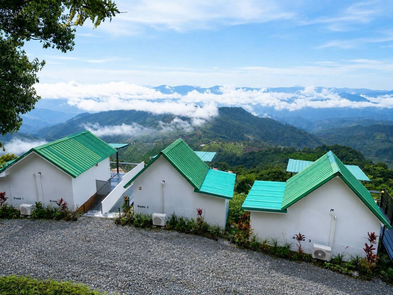 Una hilera de edificios blancos con techos verdes, con montañas al fondo.