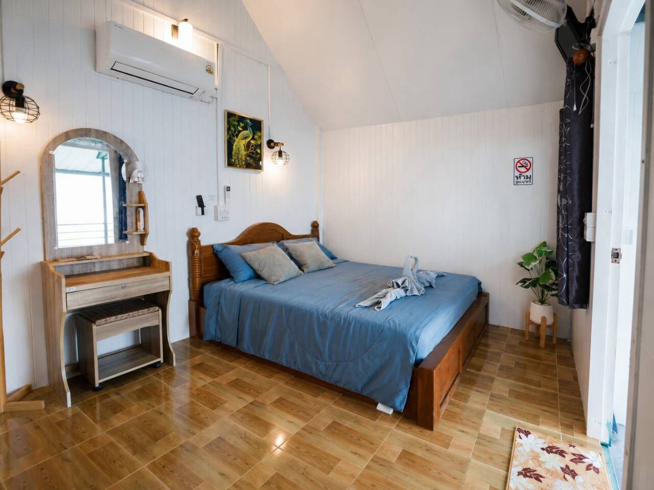A bedroom with a bed, a desk, and a mirror.