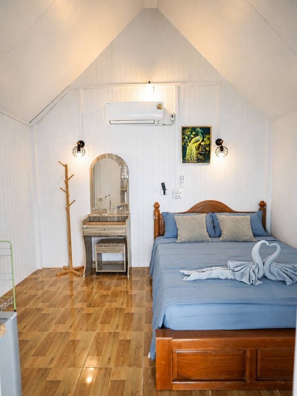 Quarto com cama de madeira, escrivaninha com cadeira, espelho e ar condicionado fixado na parede.