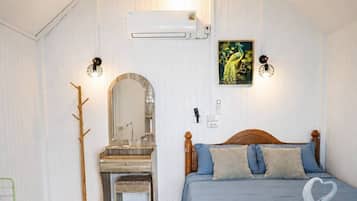 Quarto com cama de madeira, escrivaninha com cadeira, espelho e ar condicionado fixado na parede.