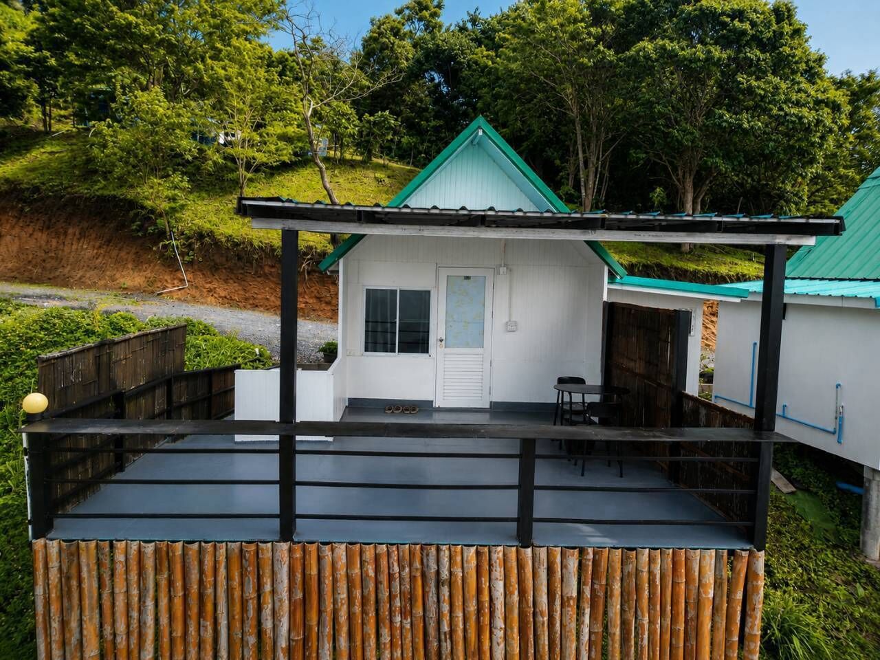 Uma casa pequena com telhado verde, varanda e deck de madeira.