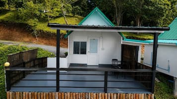 Uma casa pequena com telhado verde, varanda e deck de madeira.