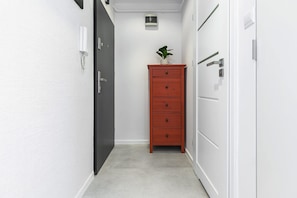 A narrow hallway with a black door, a red dresser, and a small potted plant. - House in Porspoder by Plage du Bourg Beach (Warsaw)