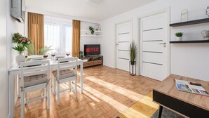 Ein modernes Wohnzimmer mit Essbereich, einem Flachbildfernseher und einem Bücherregal.