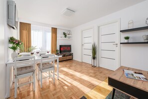 A modern living room with a dining area, a flat-screen TV, and a bookshelf. - House in Porspoder by Plage du Bourg Beach (Warsaw)