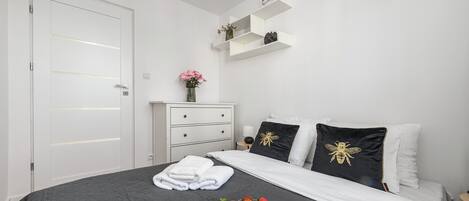 Un dormitorio con cama, cómoda, mesita de noche y estante de pared.
