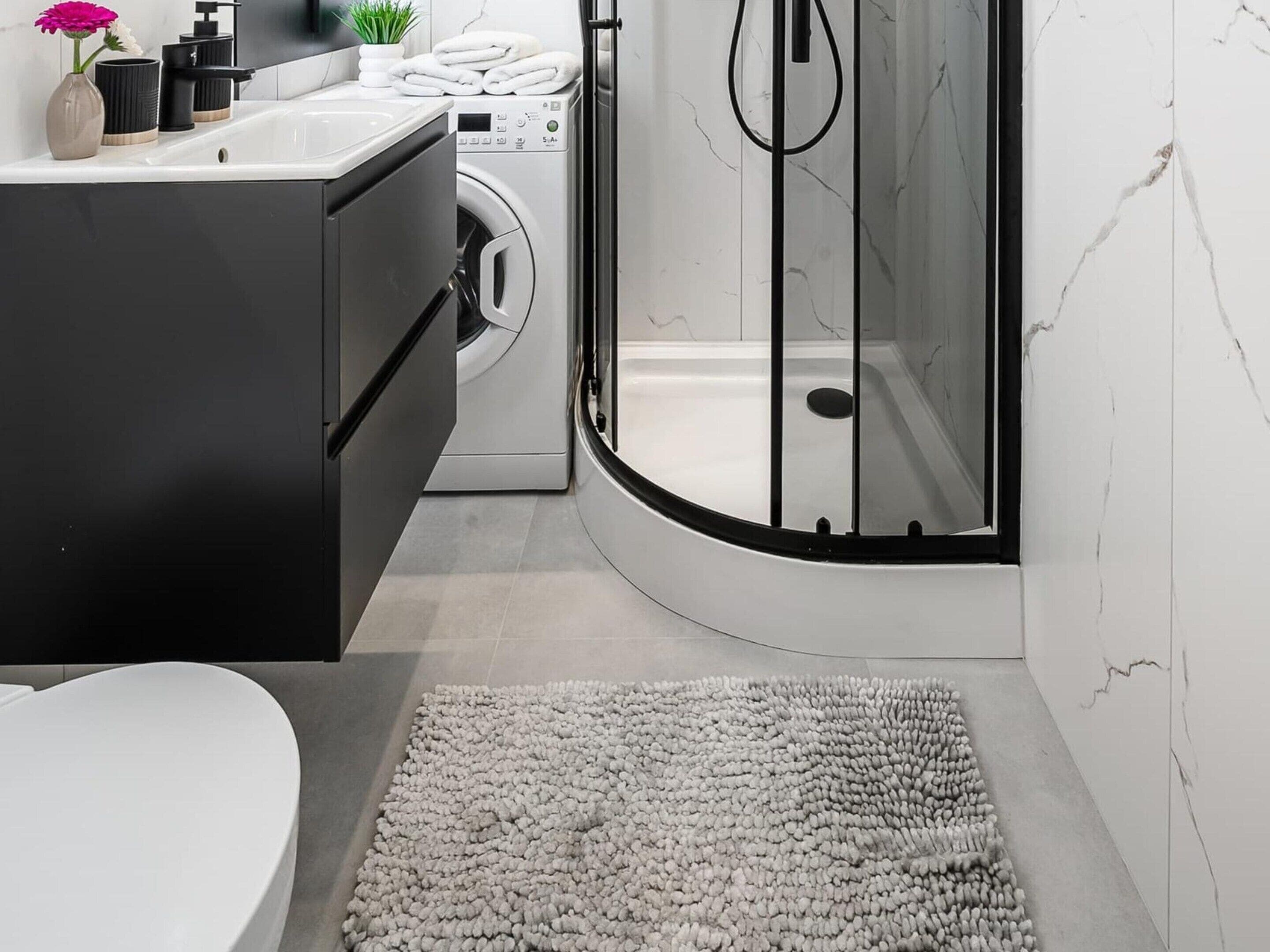Een moderne badkamer met een ingebouwde wasmachine, een douchecabine en een toilet.