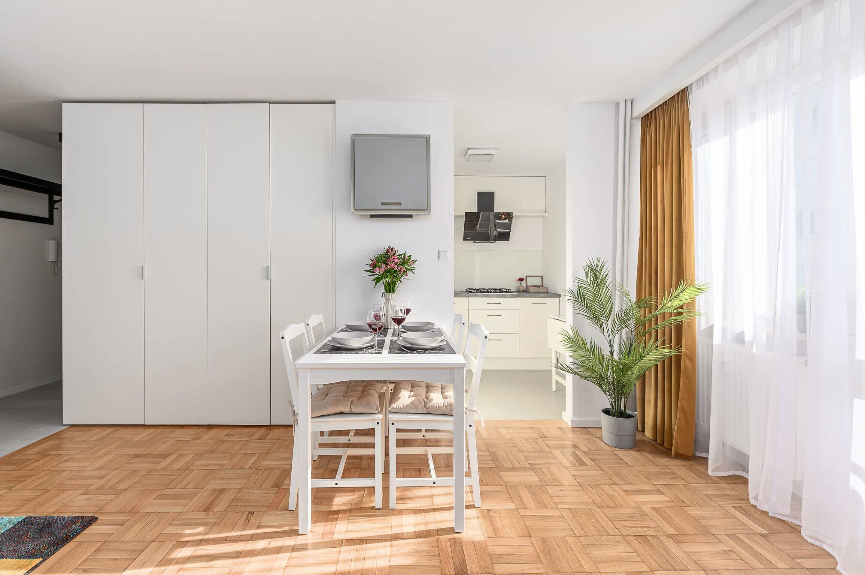 A modern kitchen with white cabinets, a built-in oven, and a flat-screen TV mounted above the counter.