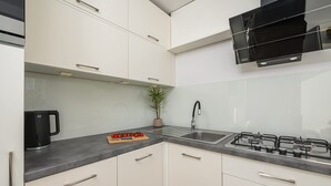 Eine moderne Küche mit weißen Schränken, einem Gaskochfeld, einer Spüle und einer Kaffeemaschine.