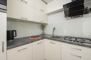 A modern kitchen with white cabinets, a gas stove, a sink, and a coffee maker. - House in Porspoder by Plage du Bourg Beach (Warsaw)