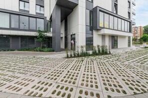 A modern building with a flat roof, large windows, and a paved area with circular cutouts. - Family Home Steps From the Beach (Warsaw)