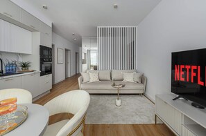 A modern living room with a sofa, coffee table, and a TV displaying 'NETFLIX'. - Family Home Steps From the Beach (Warsaw)