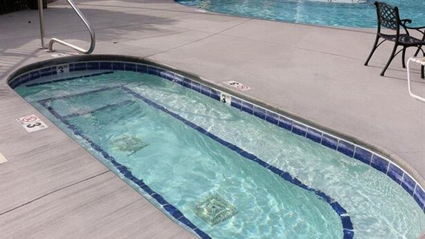 A swimming pool with lane dividers, a lifeguard chair, and a poolside chair.