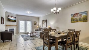A dining area with a table set for four, surrounded by wooden chairs, a chandelier, and artwork on the walls.
