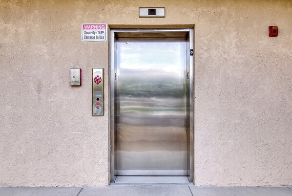An elevator with a warning sign for security cameras in use.
