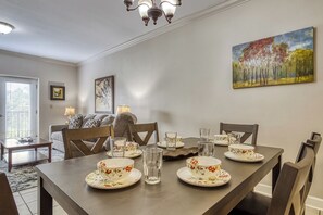 Un coin repas avec une table dressée pour quatre personnes, des chaises, un lustre et des œuvres d’art accrochées aux murs.