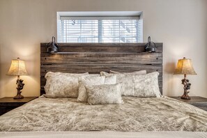 A bed with a headboard made of horizontal wooden planks, flanked by two wall-mounted lamps. - Gorgeous 3-bedroom condo with AC in welcoming Pigeon Forge! (Pigeon Forge)