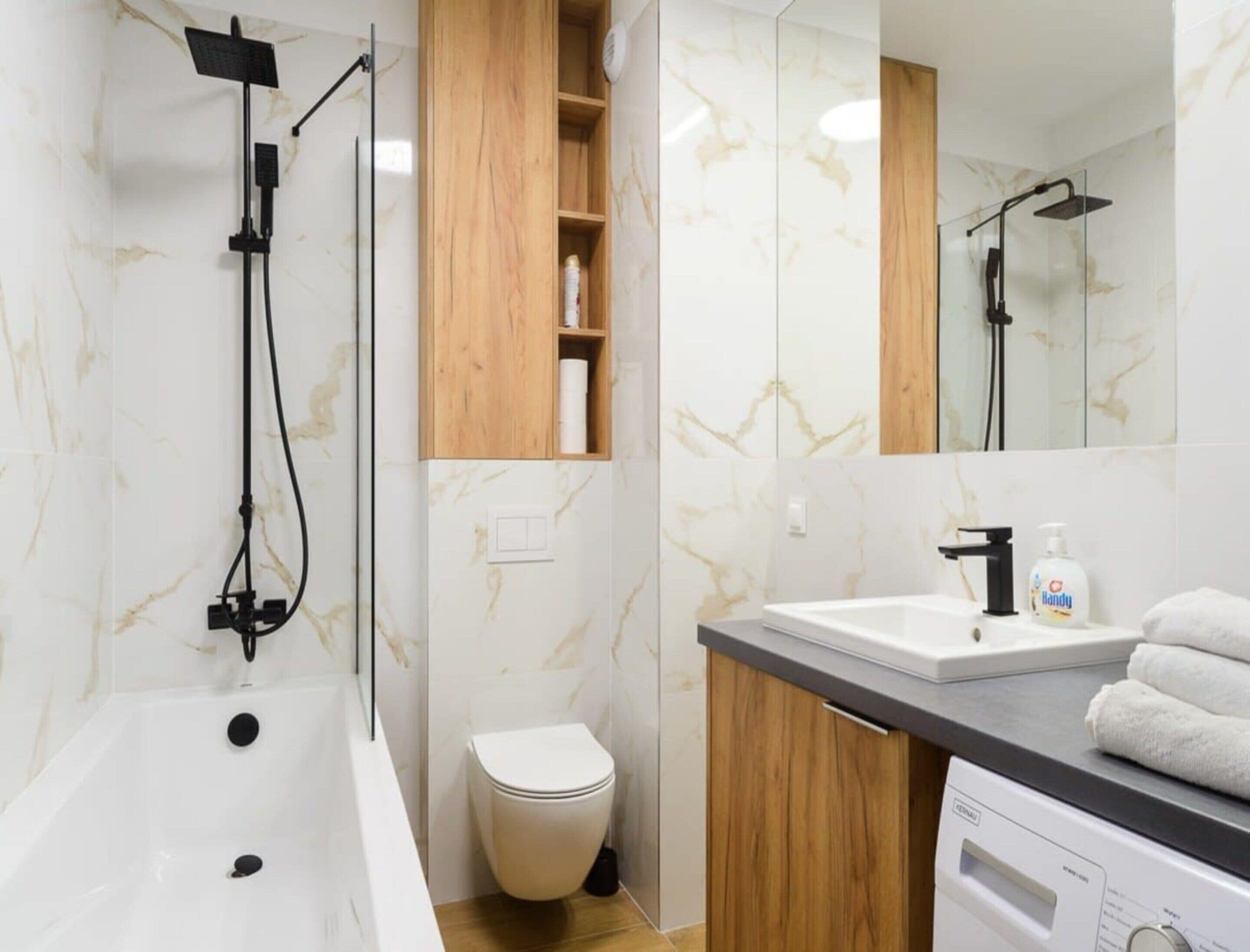 A modern bathroom with a bathtub, toilet, and a vanity with a sink and mirror.