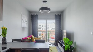 A modern kitchen with a dining area, a large window, and a view of buildings outside. - Quiet City Apartment for 4 (Łódź)