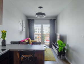 A modern kitchen with a dining area, a large window, and a view of buildings outside. - Quiet City Apartment for 4 (Łódź)