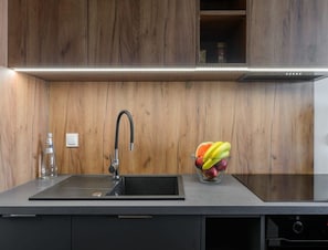 Eine Küche mit einem modernen Wasserhahn, einem Glas Wasser und einer Schüssel mit Obst auf der Arbeitsfläche.