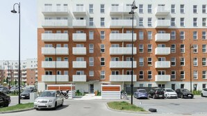 A multi-story residential building with balconies, a parking area, and a street lamp. - Quiet City Apartment for 4 (Łódź)
