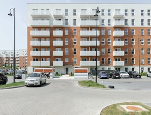 A multi-story residential building with balconies, a parking area, and a street lamp. - Quiet City Apartment for 4 (Łódź)