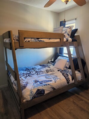 Ein Stockbett mit Holzrahmen und gemusterten Bettbezügen.