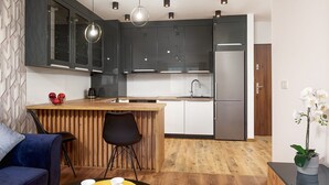 A modern kitchen with dark cabinets, a wooden island, and a stainless steel refrigerator. - City View Apartment in Warsaw (Łódź)