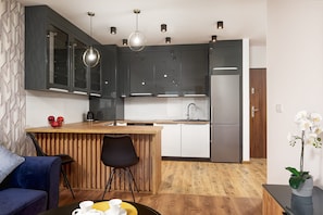 A modern kitchen with dark cabinets, a wooden island, and a stainless steel refrigerator. - City View Apartment in Warsaw (Łódź)