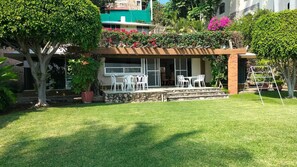 A residential property with a well-maintained lawn, a patio with outdoor furniture, and a variety of plants and flowers.