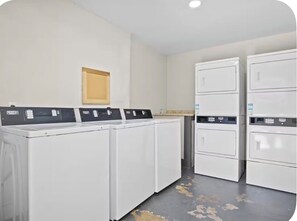 Ein Waschraum mit vier weißen Waschmaschinen und einem an der Wand befestigten Holzschrank.