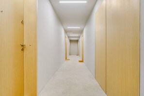 A corridor with wooden doors on both sides, a carpeted floor, and overhead lighting. - Stay Near Railway Hub (Warsaw)