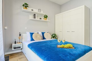A bedroom with a bed, bedside tables, a wardrobe, and a window. - Stay Near Railway Hub (Warsaw)