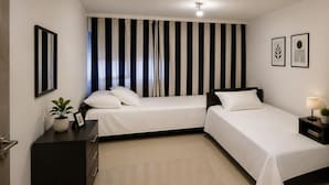 A hotel room with two beds, a dark wardrobe, a bedside table with a lamp, and a potted plant. - Charming  Affordable Room in Geneva Close to Tram 15 & Bus 11 (Genève)