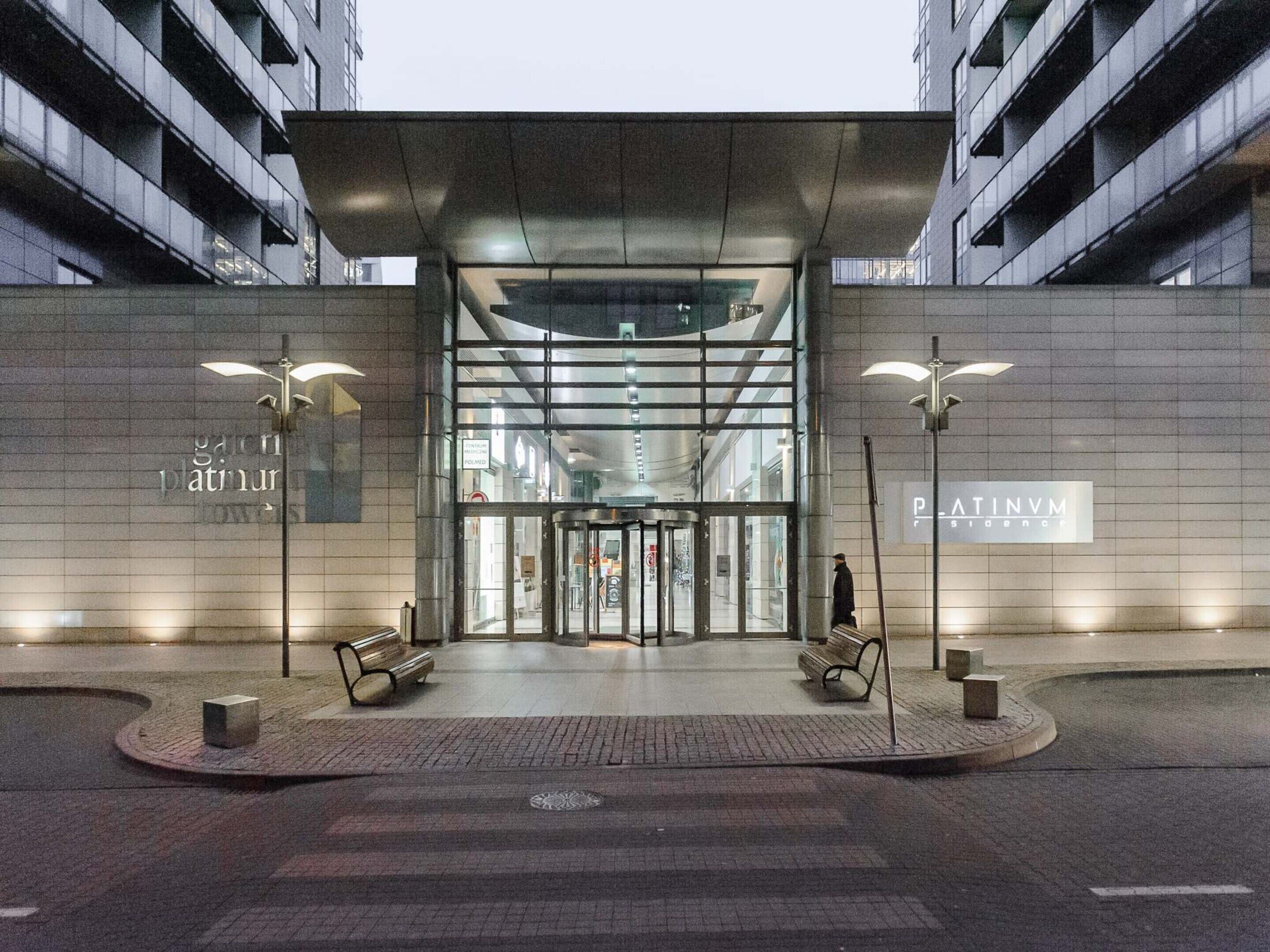Une entrée moderne avec une porte tournante, des bancs et une vue dégagée sur l’intérieur du bâtiment.