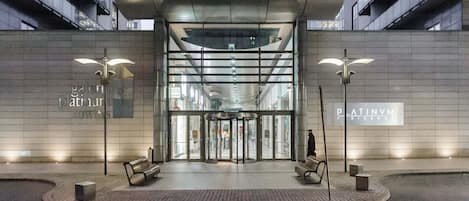 Vestíbulo moderno de un edificio con puerta giratoria, bancos y vista despejada al interior.