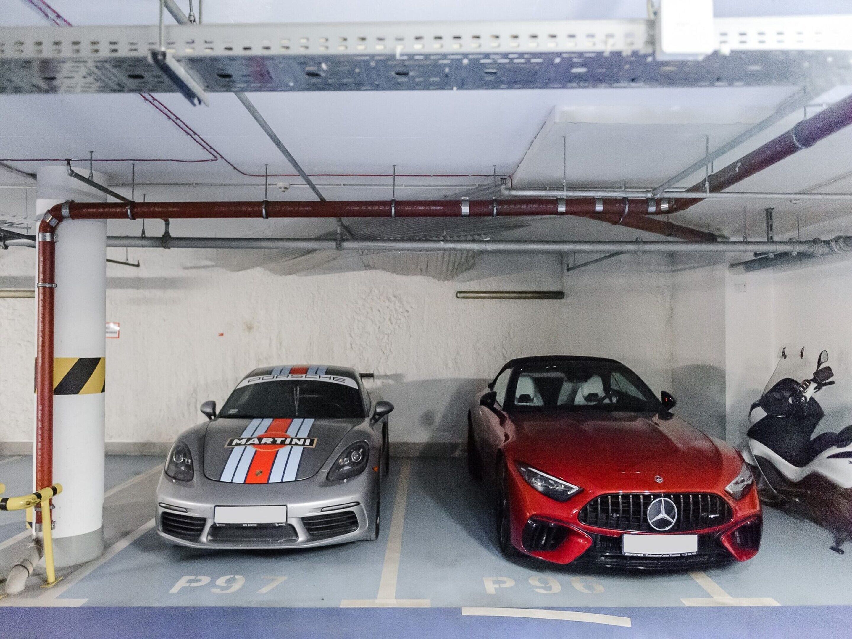 Uma garagem de estacionamento com dois carros, um com um logotipo visível e outro com uma insígnia visível.