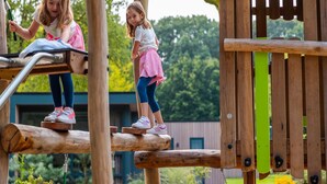 Two children playing on a wooden play structure with a slide and climbing elements. - Charming Chalet Near Efteling (Kaatsheuvel)