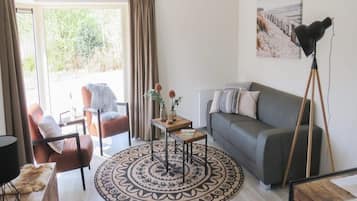 A living room with a sofa, a chair, a coffee table, and a floor lamp.