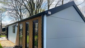 A modern building with a sloped roof, a number '398' sign, and a series of doors with vertical wooden slats. - Charming Chalet Near Efteling (Kaatsheuvel)