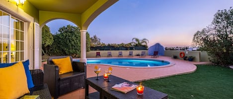 Un espacio al aire libre cubierto con piscina, asientos y vistas del paisaje circundante.