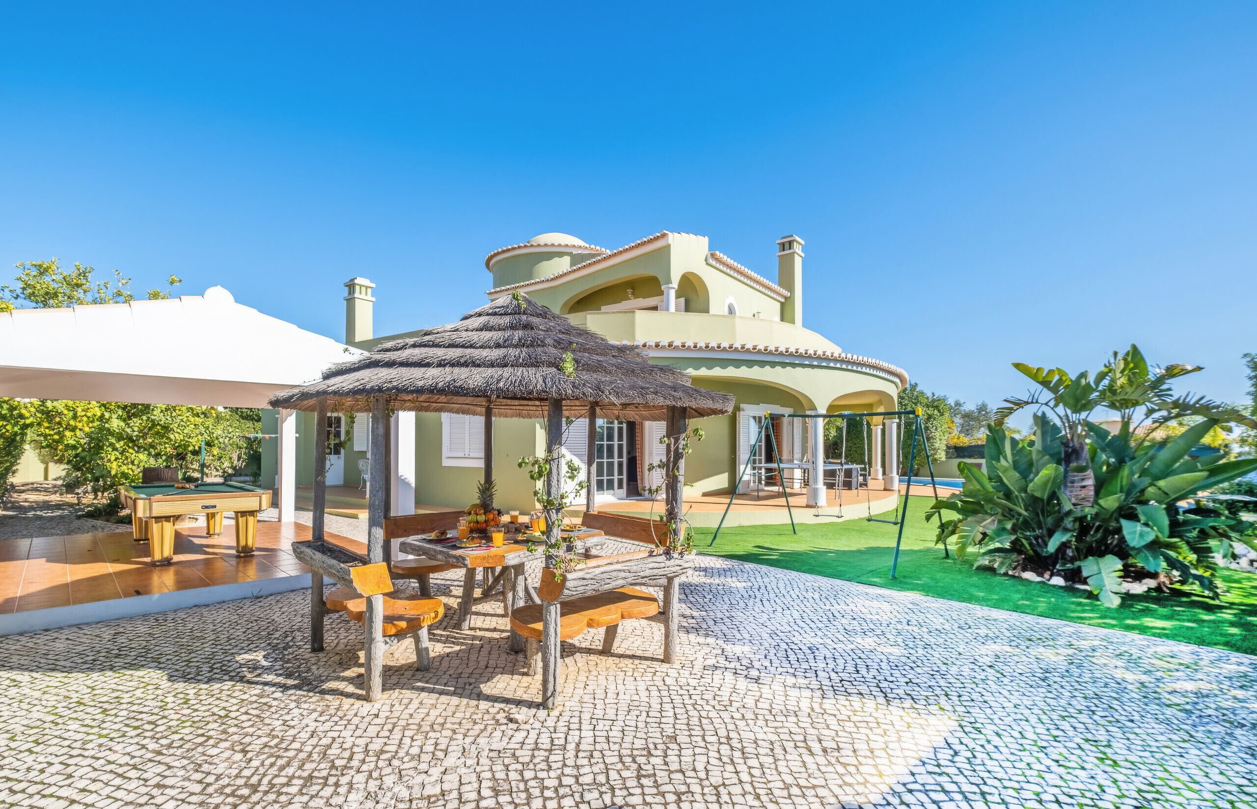 A villa with a pool, outdoor seating, and a garden.
