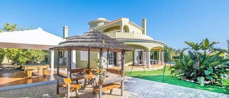 A villa with a pool, outdoor seating, and a garden.